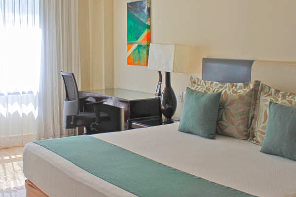 Escritorio funcional con silla ergonómica y conexiones eléctricas para laptop en habitación de Smart Cancun