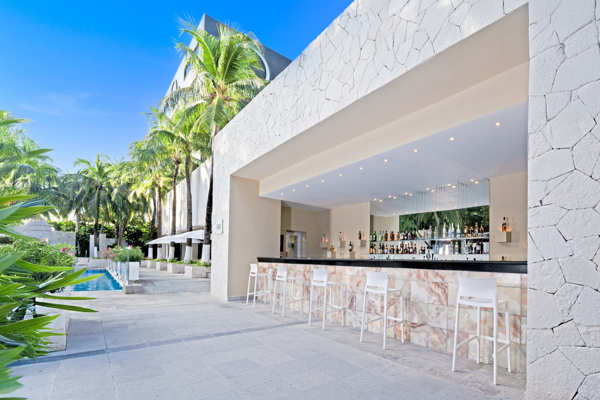 Bar de alberca al aire libre con coctelería tropical en la terraza del hotel Smart Cancun